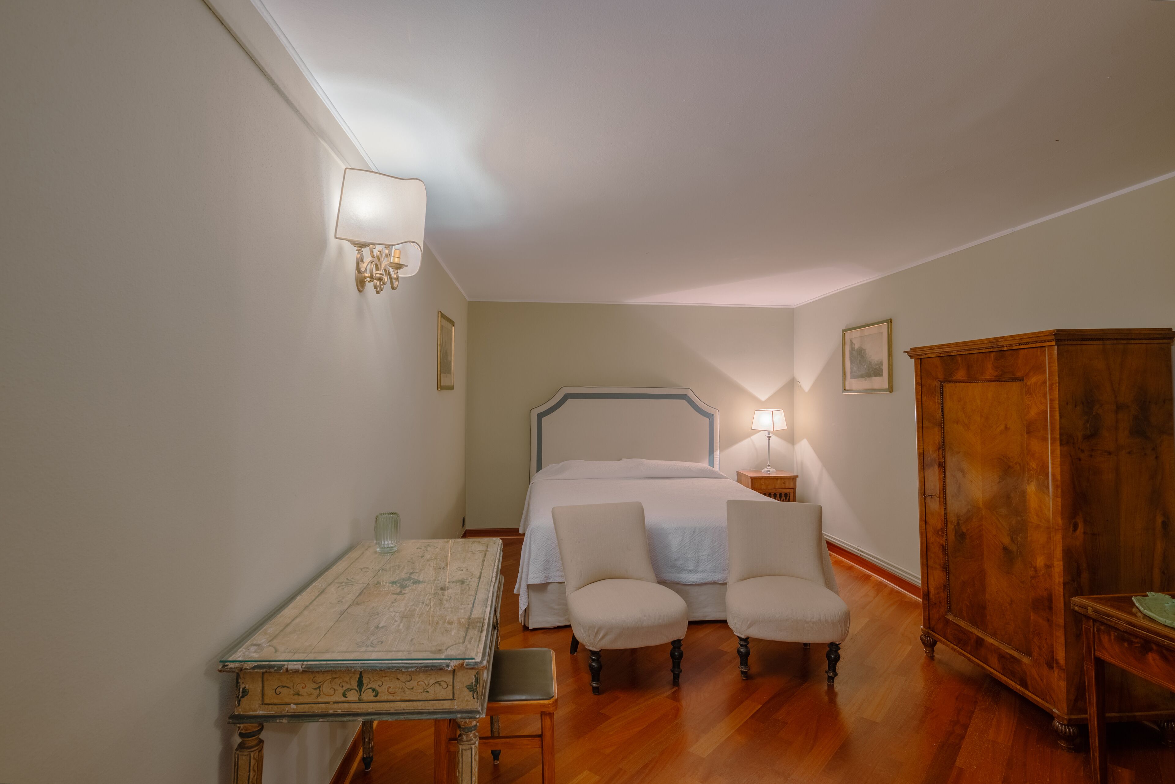 Une chambre à coucher avec un lit, deux chaises, une armoire en bois et une table.