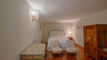 Une chambre à coucher avec un lit, deux chaises, une armoire en bois et une table.