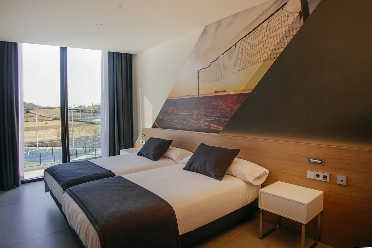 A hotel room with two beds, a large window, and a view of the beach.
