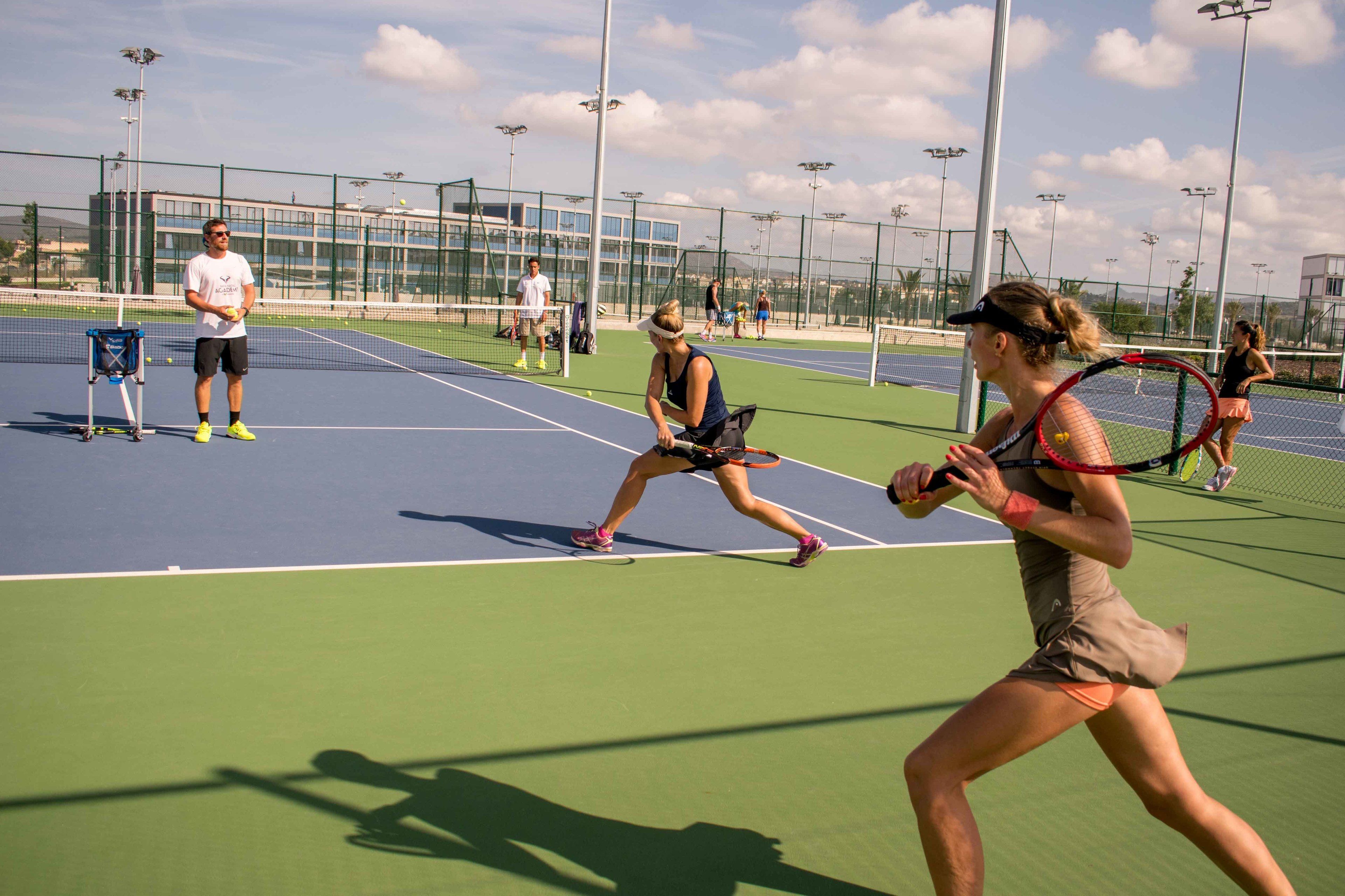 A tennis court with players in action, a net, and a fence surrounding the court.
