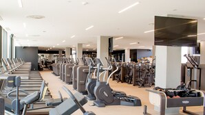 Un gimnasio moderno con cintas de correr, elípticas y estaciones de pesas.
