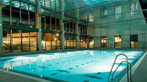 Una piscina interior con carriles delimitados, rodeada de amplios ventanales y un diseño arquitectónico moderno.