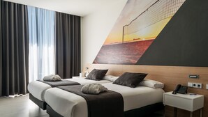 Habitación de hotel moderna con una cama grande, una mesita de noche con teléfono y un televisor montado en la pared.