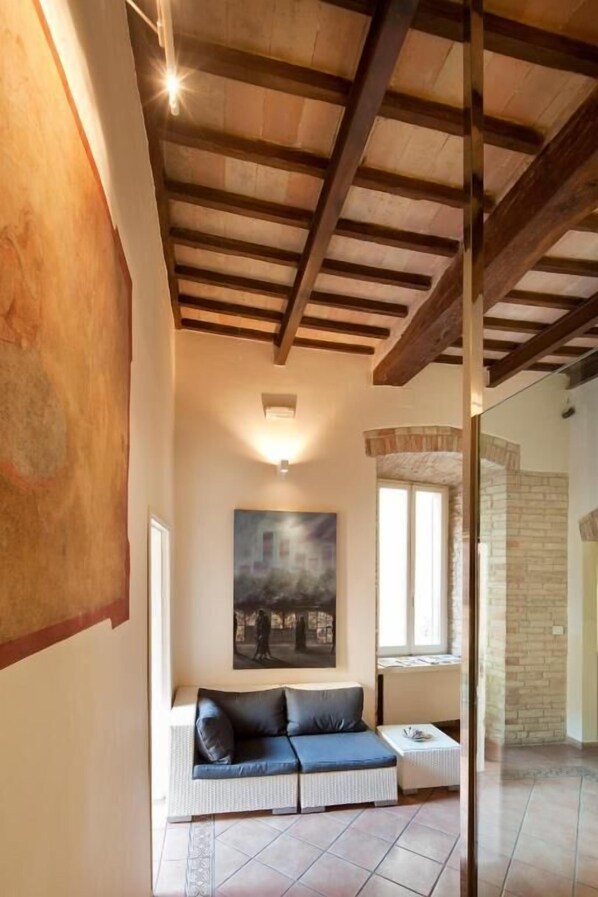 A cozy living room with a sofa, a painting, and a window.
