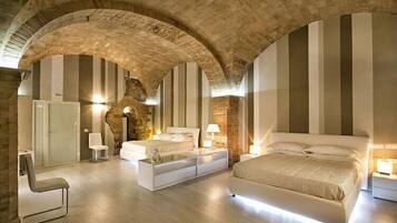 Un dormitorio moderno con techo abovedado de piedra, una cama grande, mesitas de noche y una zona de estar.