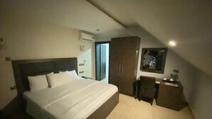 Un dormitorio con una cama grande, un armario, un escritorio y una ventana.