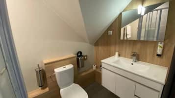 Une salle de bain moderne avec des toilettes blanches, un lavabo et un miroir.