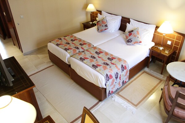 Habitación de hotel con una cama grande, dos mesitas de noche, un escritorio con silla y una pequeña mesa con otra silla.