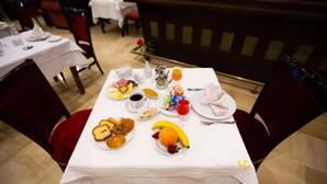 A dining table set with breakfast items including croissants, fruit, and beverages. - Hôtel Le Consul (Tunis)