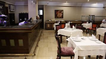 Un restaurant avec plusieurs tables dressées pour le service, un bar et un comptoir.