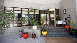 A lobby with potted plants, a trash bin, and a table with chairs. - Hôtel Le Consul (Tunis)