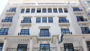 A multi-story building with a symmetrical facade, featuring evenly spaced windows and balconies with black railings. - Hôtel Le Consul (Tunis)
