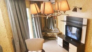 A living room with a sofa, a TV, and a chandelier. - Noubou International Hotel (Douala)
