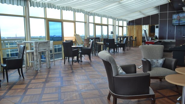 A spacious lounge with large windows, comfortable seating, and a view of the cityscape. - Noubou International Hotel (Douala)