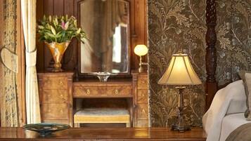 A wooden dresser with a mirror, a lamp, and a vase with flowers.