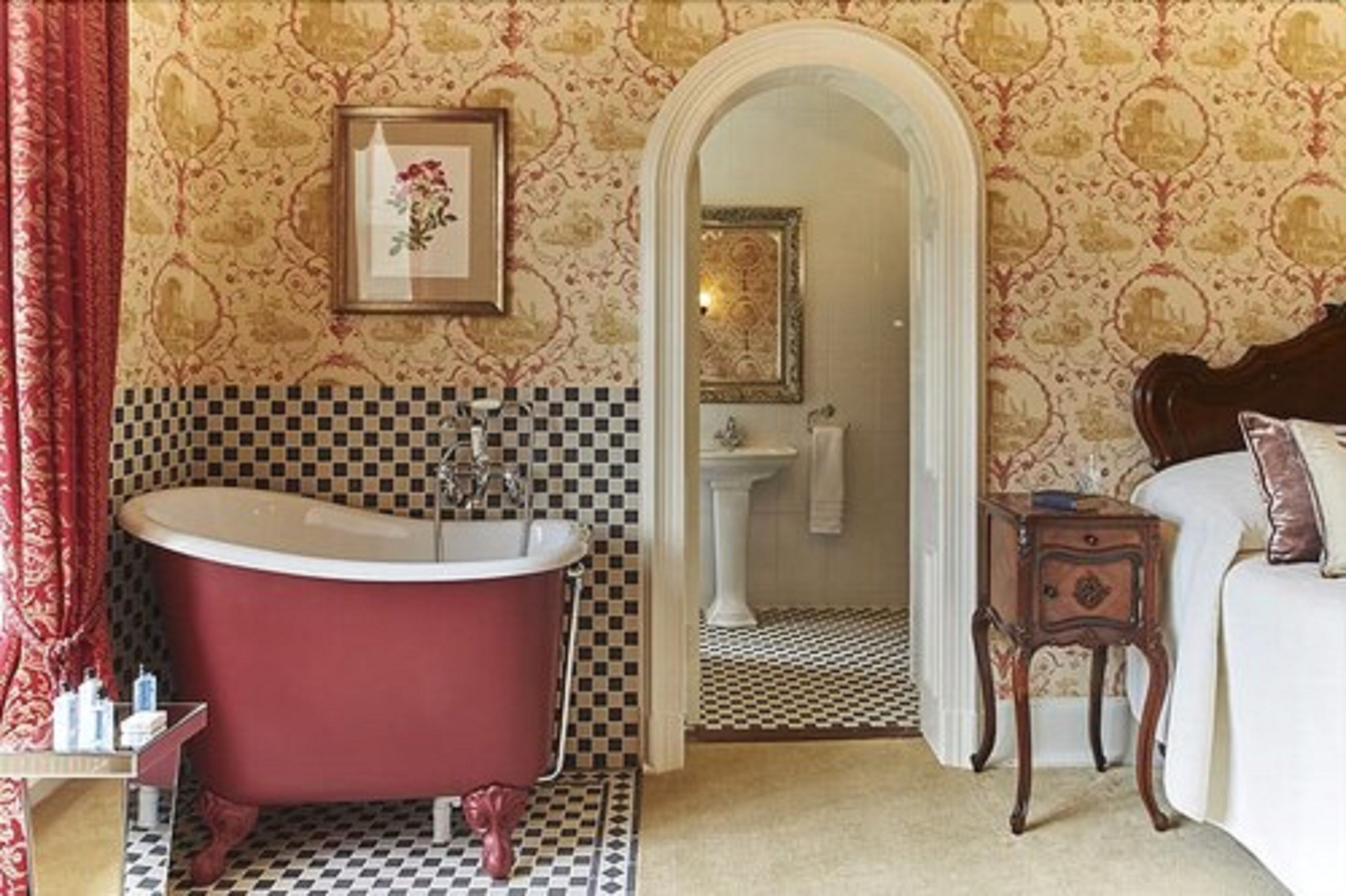 A bathroom with a red clawfoot bathtub, a white sink, and a mirror.