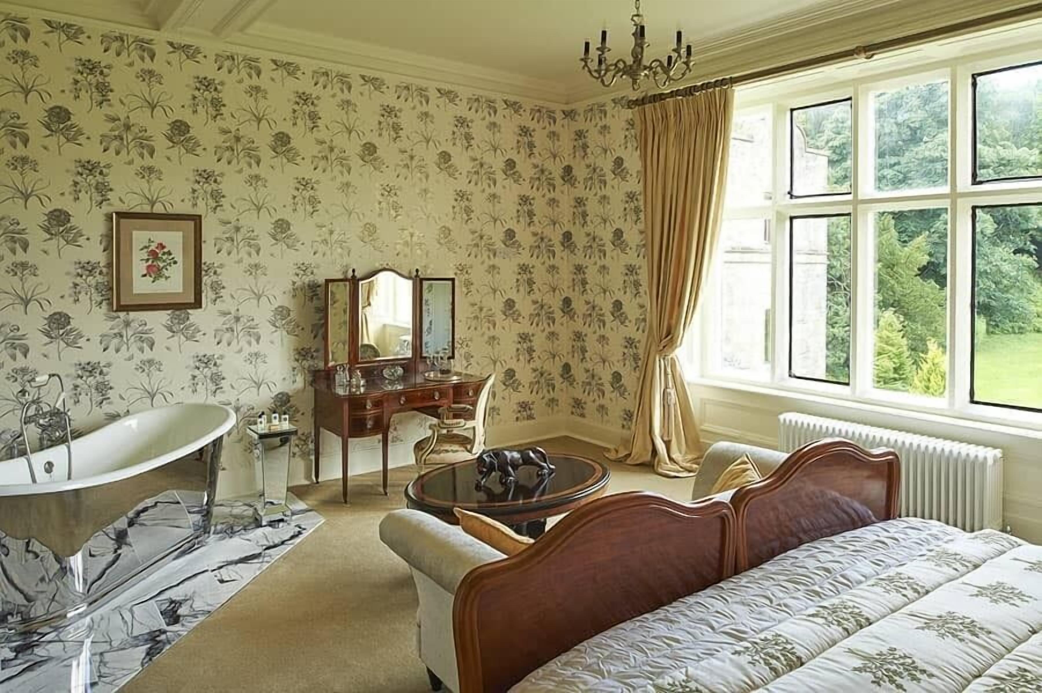 Ein Schlafzimmer mit großem Fenster, Badewanne, Schminktisch und einem Bett.