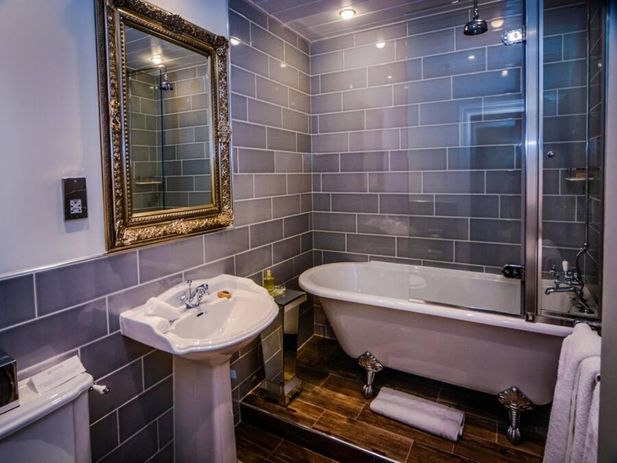 A bathroom with a white sink, a bathtub, and a mirror with an ornate frame.