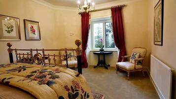 A bedroom with a bed, a chair, a table, and a window with curtains.