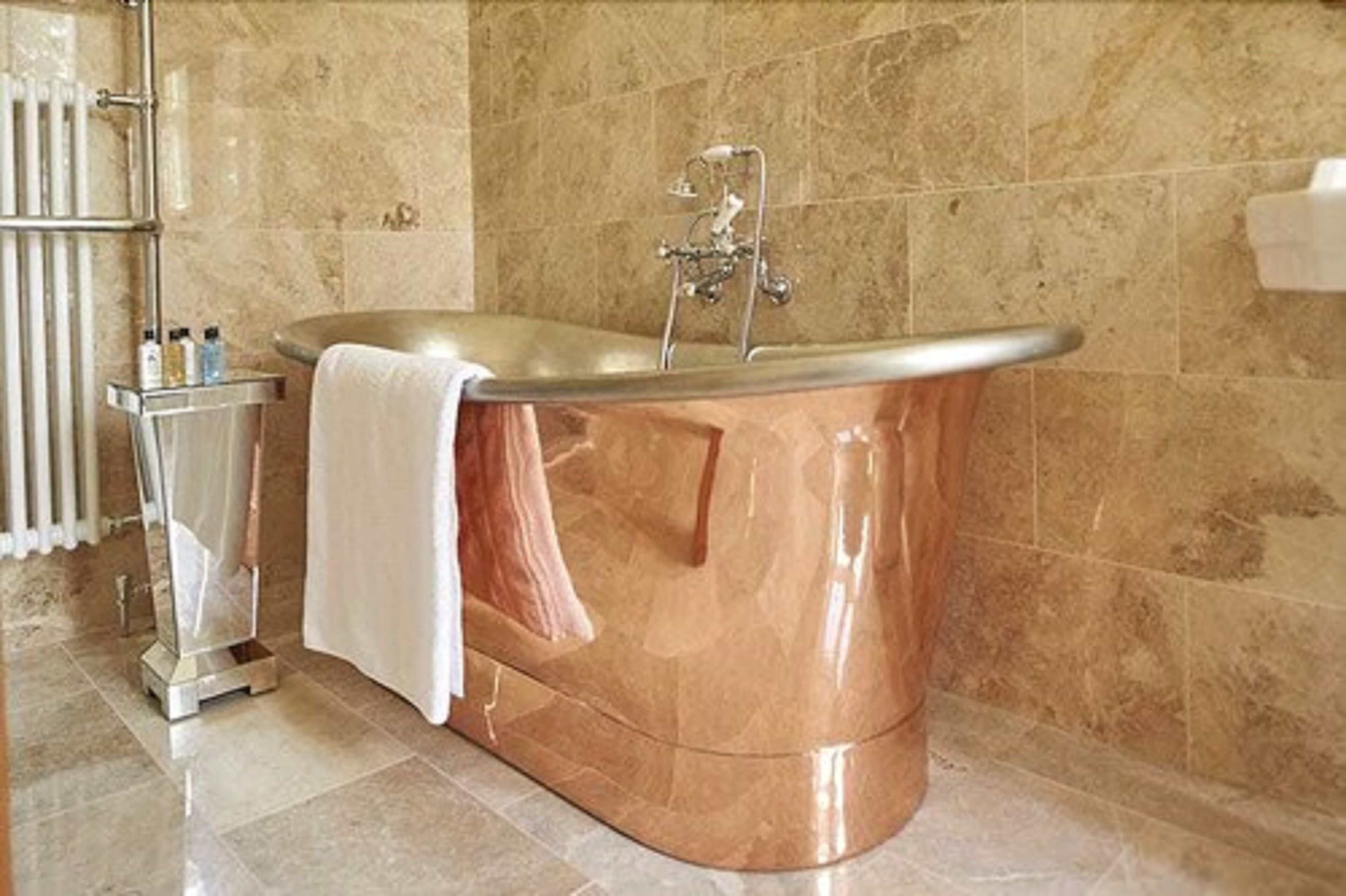 A modern bathroom with a freestanding bathtub, a towel rack, and a small shelf with toiletries.