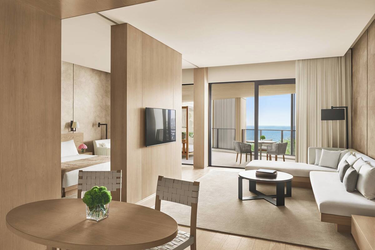 A modern hotel room with a balcony, a dining area, and a living room.