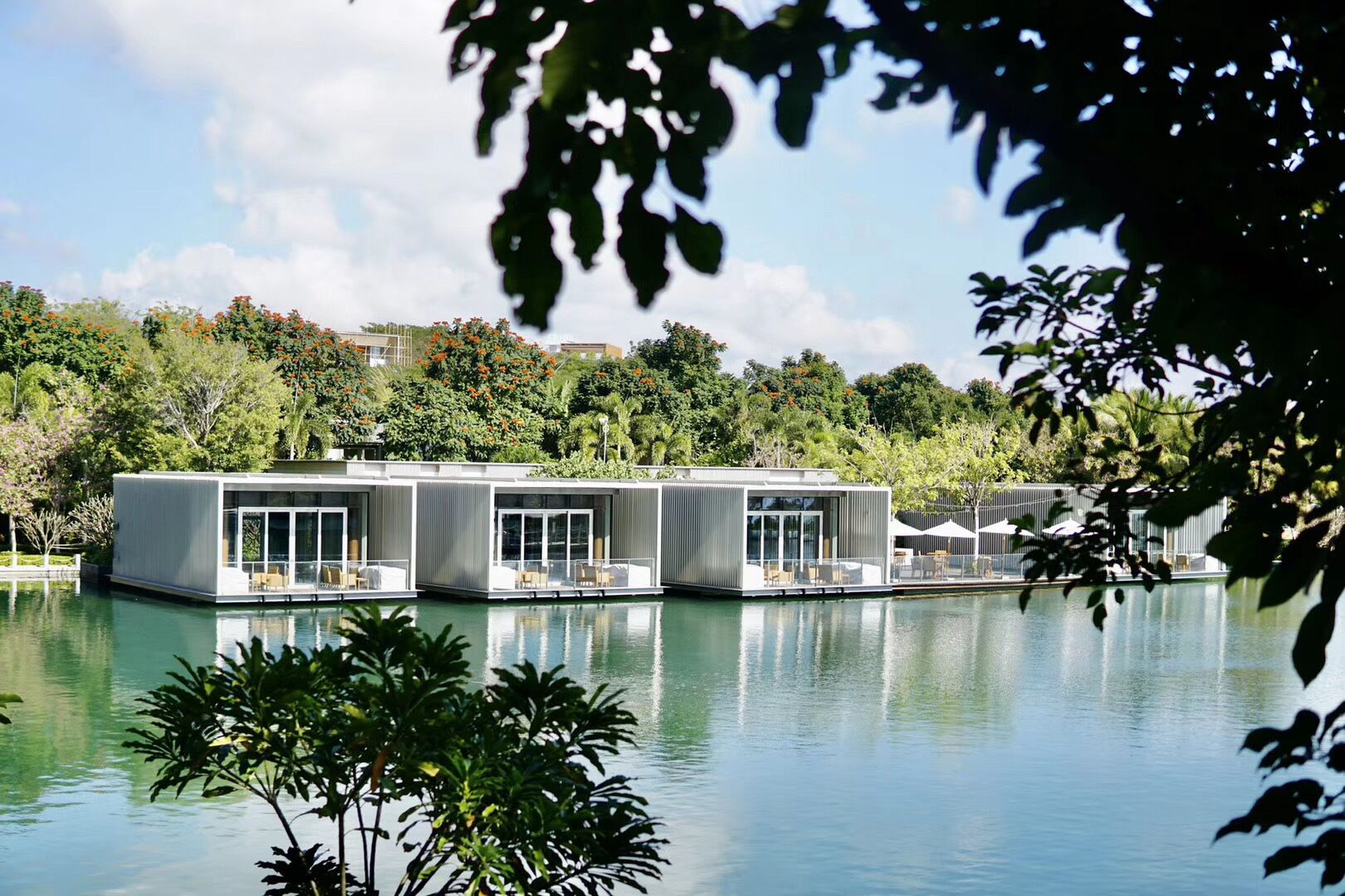 Een modern drijvend huis met meerdere verdiepingen, grote glasramen en buitenplaatsen.