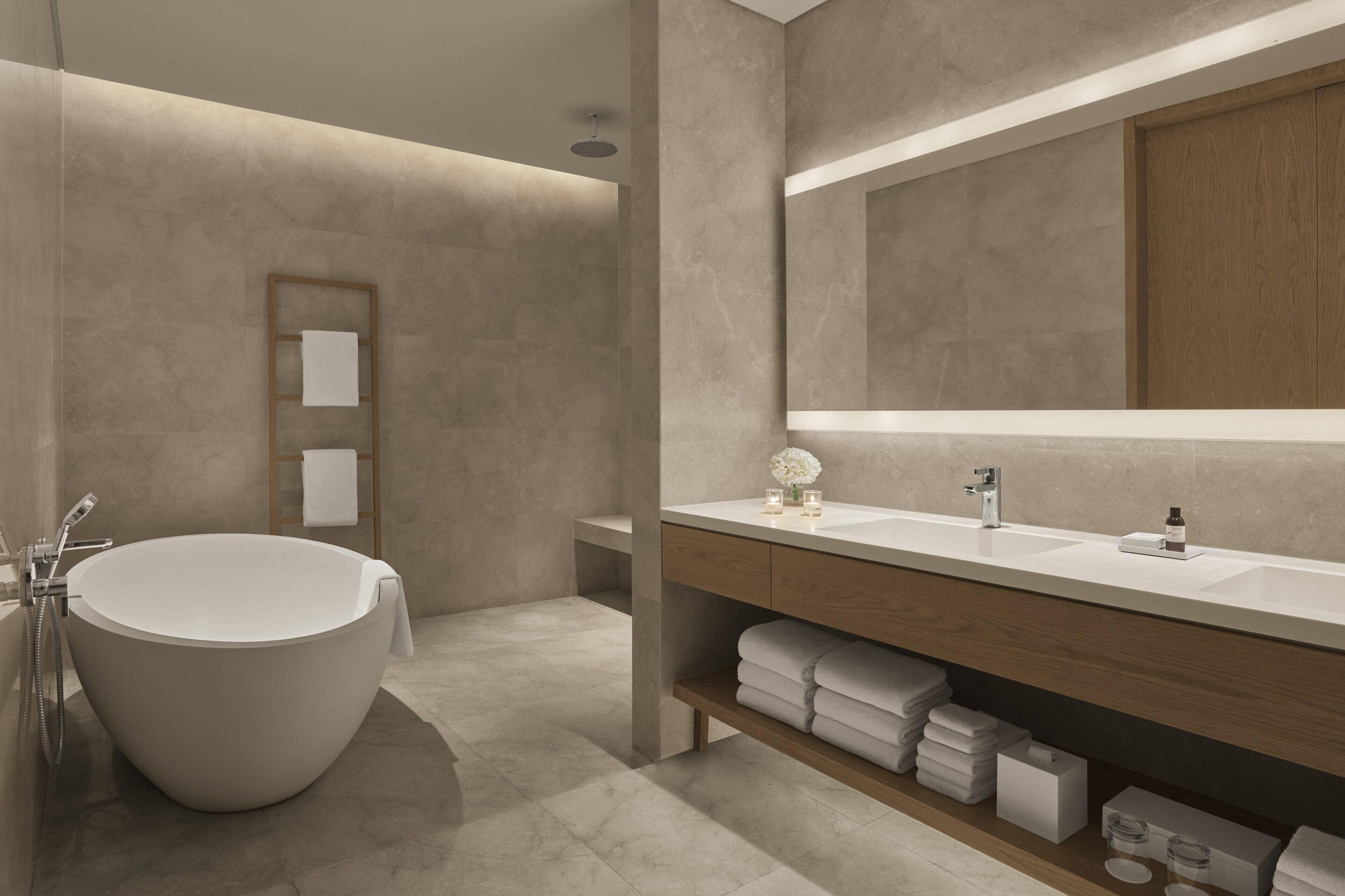 Un baño moderno con una bañera independiente, un espejo grande y un tocador con encimera de madera.