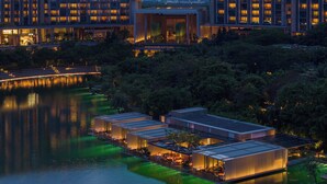 A modern hotel with a waterfront view, featuring a series of connected buildings with outdoor seating areas. - The Sanya EDITION (Sanya)
