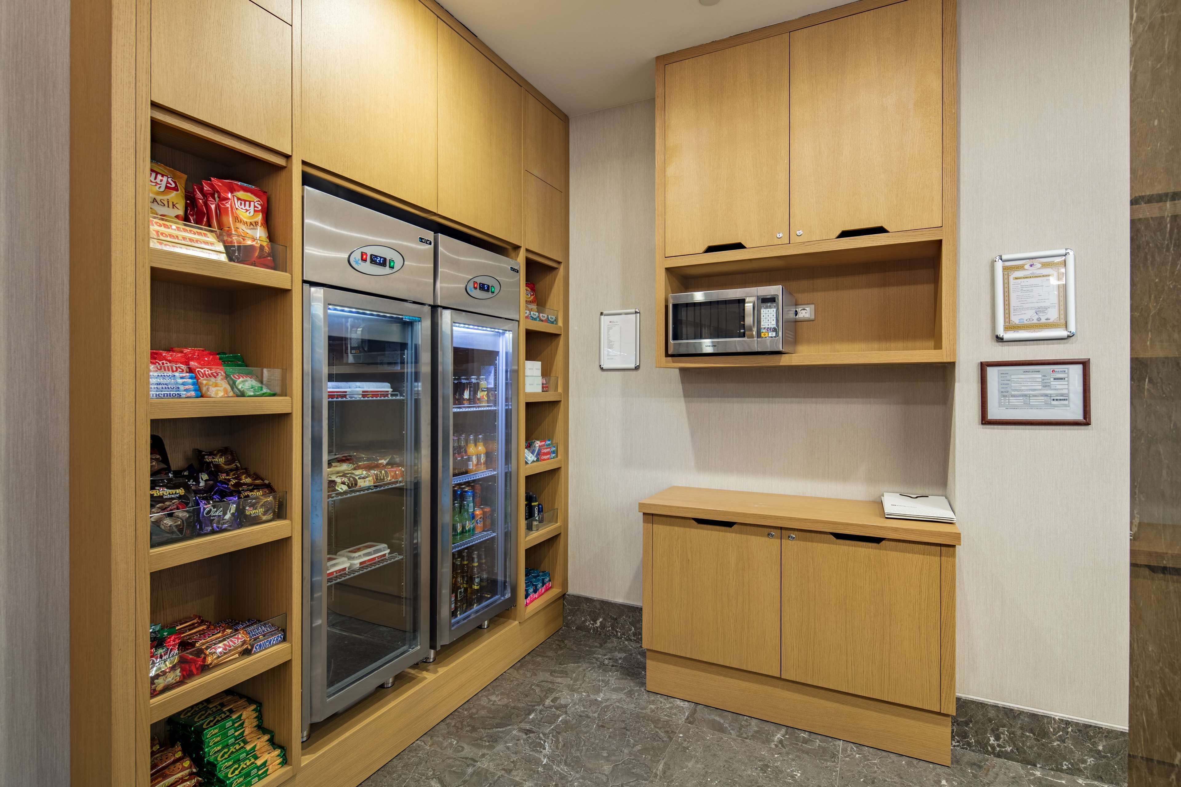 Una kitchenette con armarios de madera, un refrigerador, un microondas y una pequeña encimera.