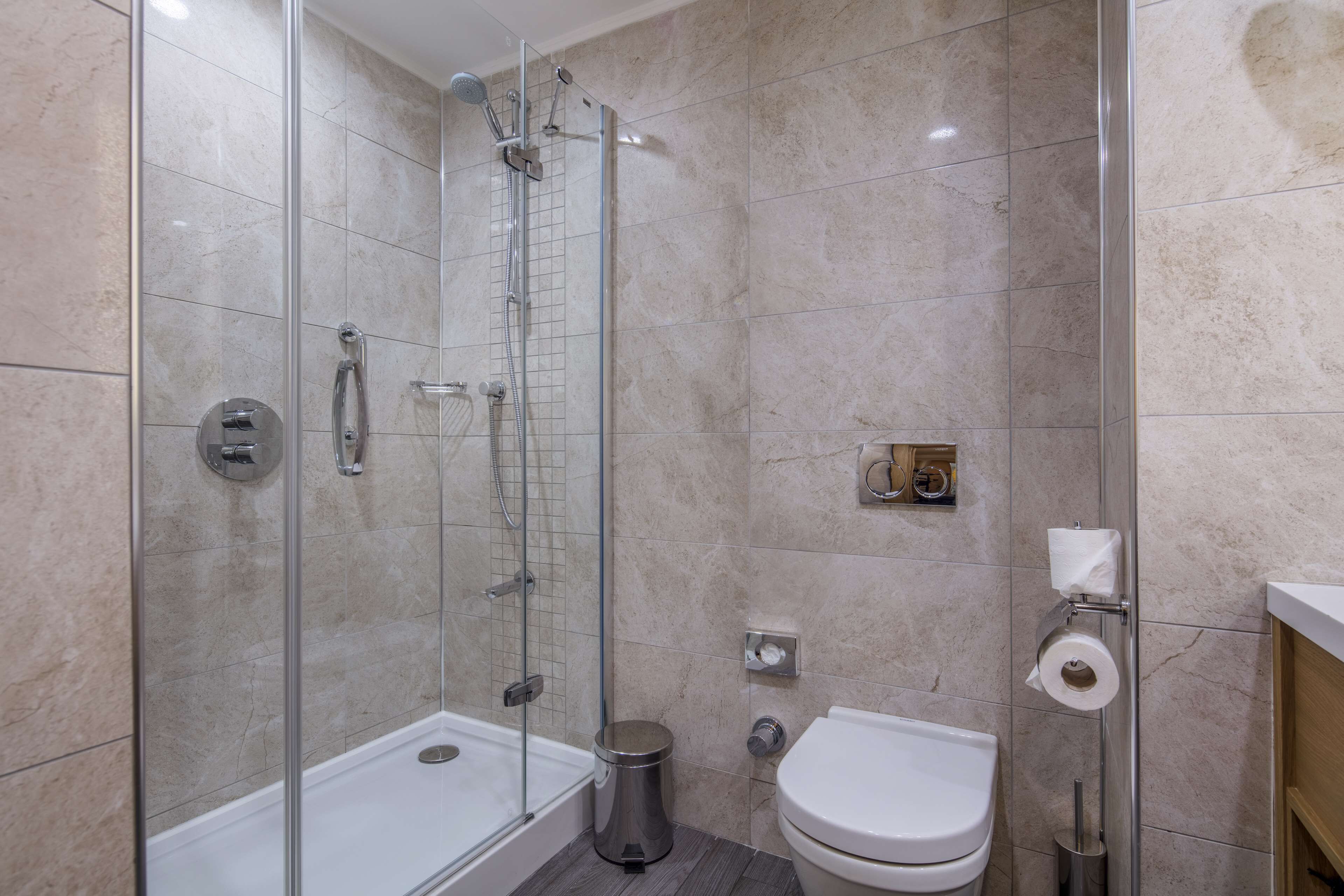 Ein modernes Badezimmer mit einer gläsernen Duschkabine, einer weißen Toilette und einem Bidet.