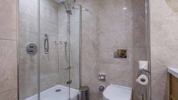 Ein modernes Badezimmer mit einer gläsernen Duschkabine, einer weißen Toilette und einem Bidet.