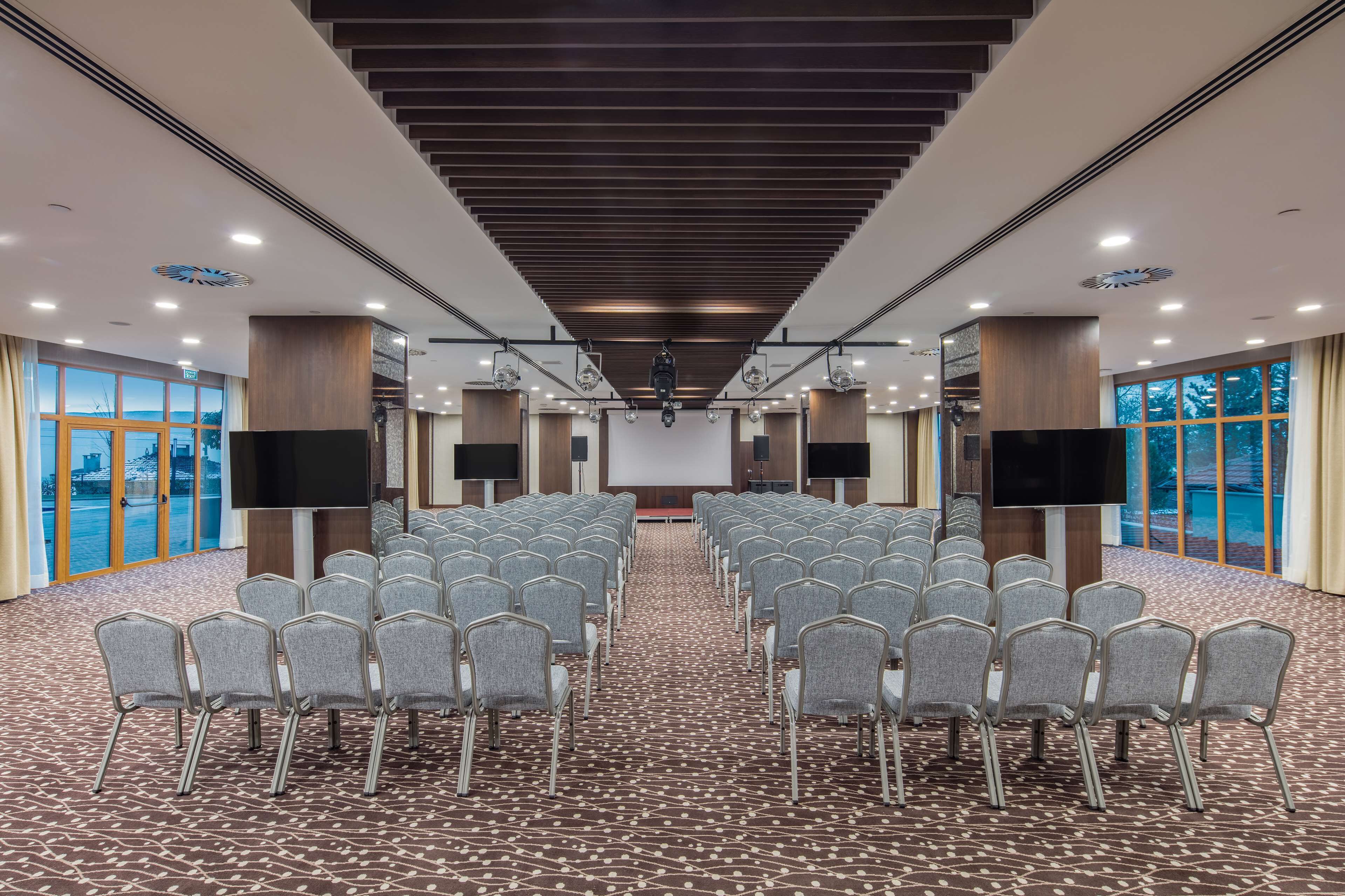 A conference room with rows of chairs, a large screen, and a stage.