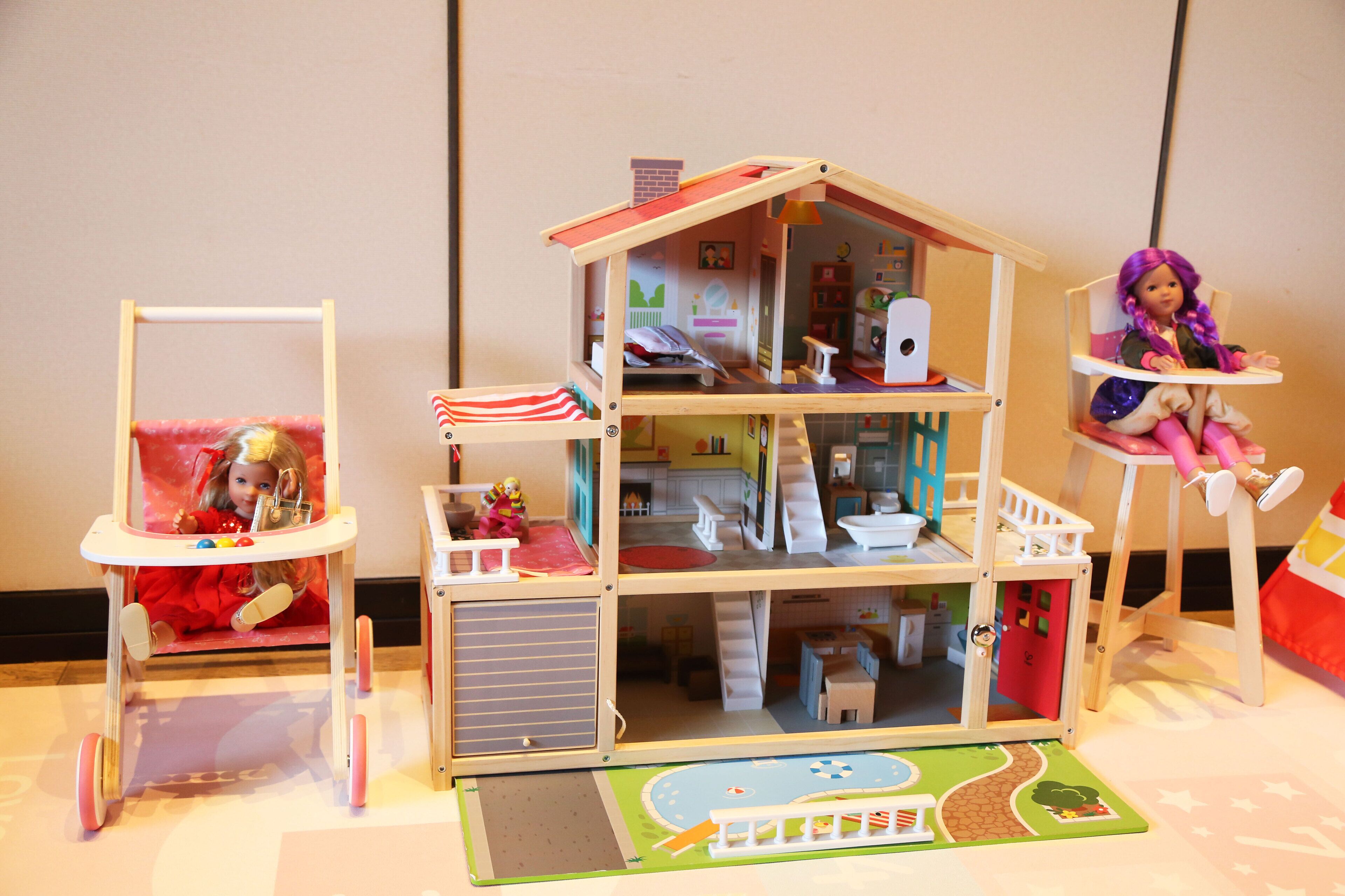 Une maison de poupée avec plusieurs pièces, dont une cuisine, un coin repas et une chambre à coucher.