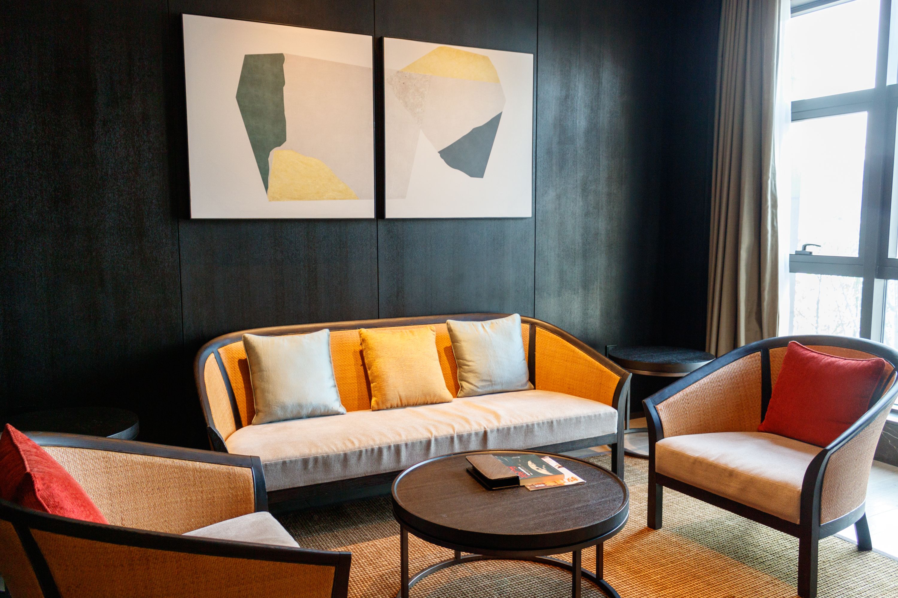 A modern room with a sofa, armchairs, a coffee table, and abstract wall art.