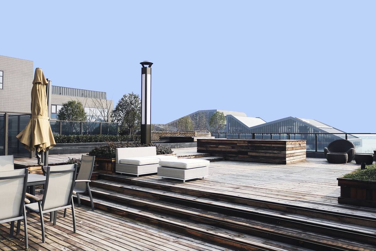 Una terraza en la azotea con mobiliario exterior, una mesa y sillas.