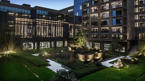 Een modern gebouwcomplex met meerdere verdiepingen, grote ramen en een goed onderhouden binnentuin met paden en groen.