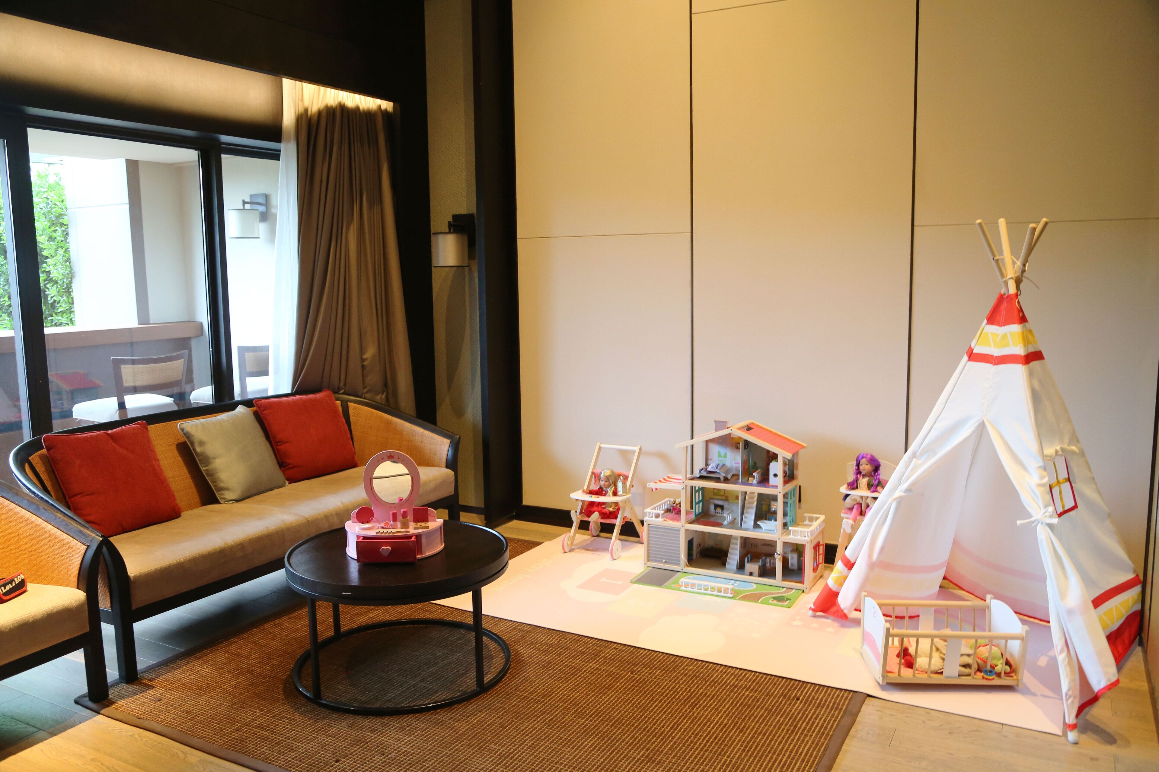 Una sala de estar con un sofá, una mesa de centro, una casa de muñecas y un tipi.