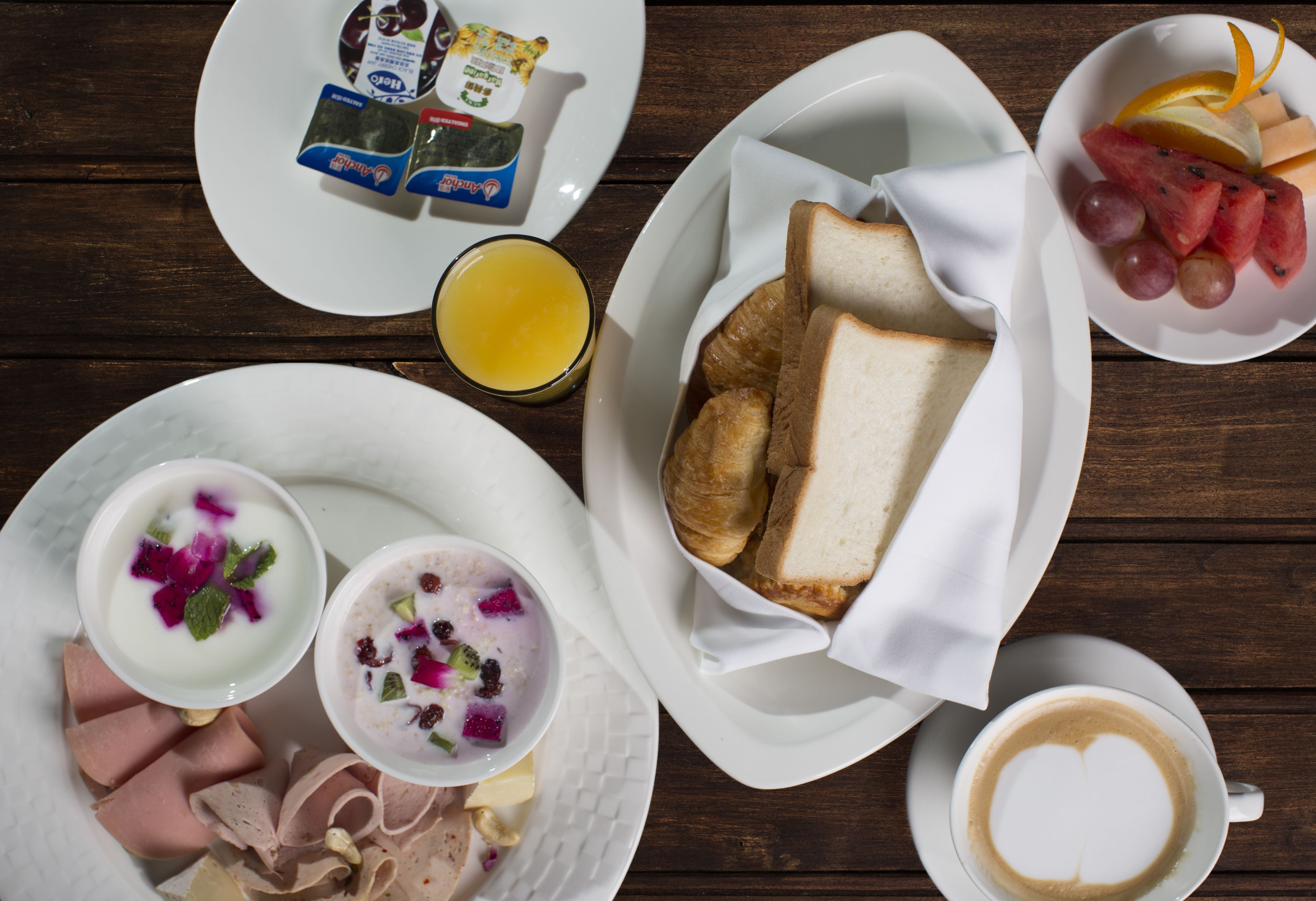 A breakfast setting with various food items and beverages on a wooden table.