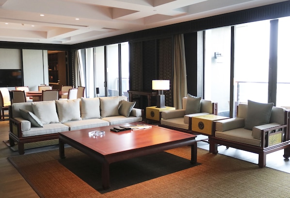 Un hall d’hôtel spacieux, avec une grande table basse en bois, deux canapés et un téléviseur.