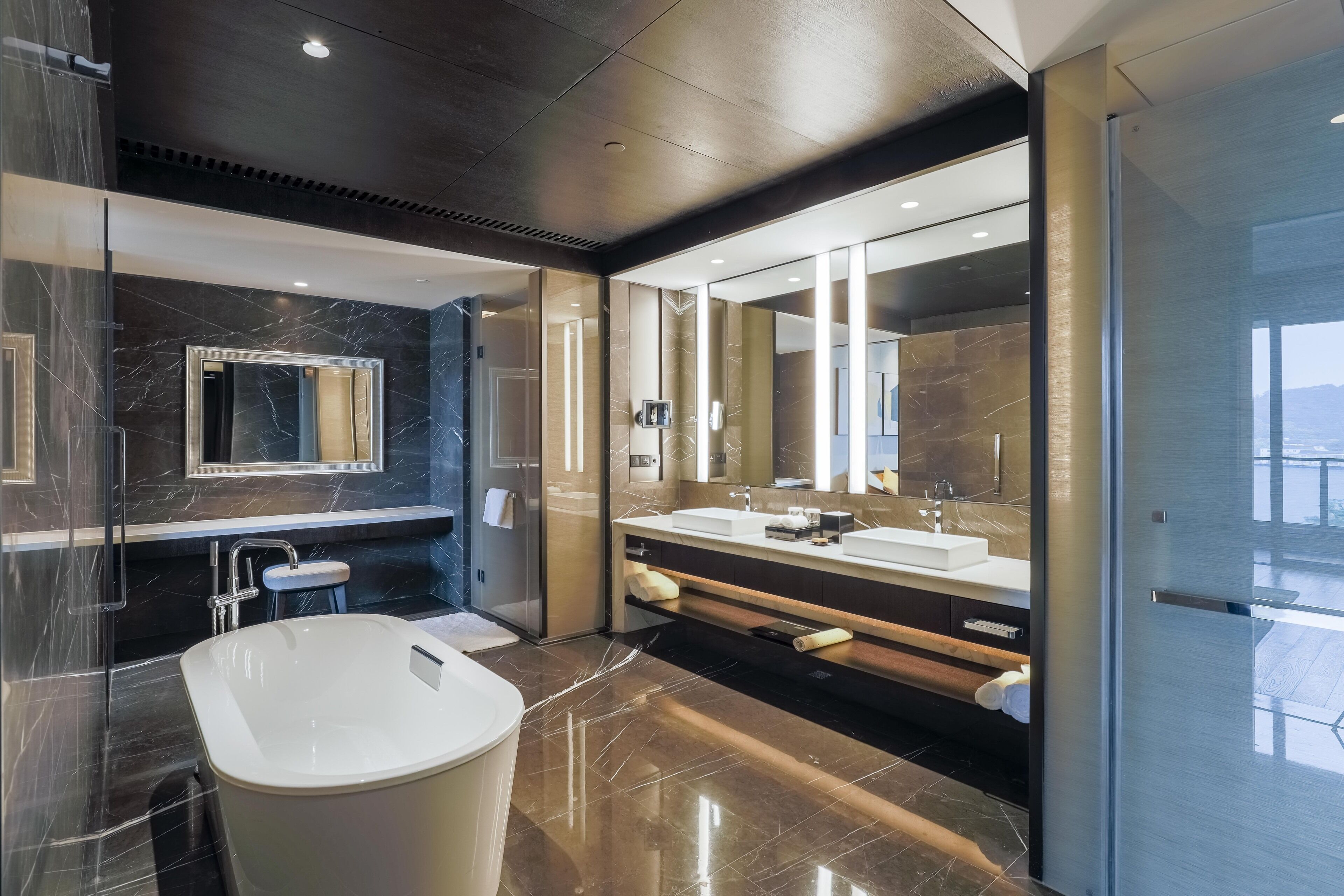 A modern bathroom with a large bathtub, a double sink vanity, and a large mirror.