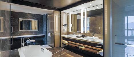 A modern bathroom with a large bathtub, a double sink vanity, and a large mirror.