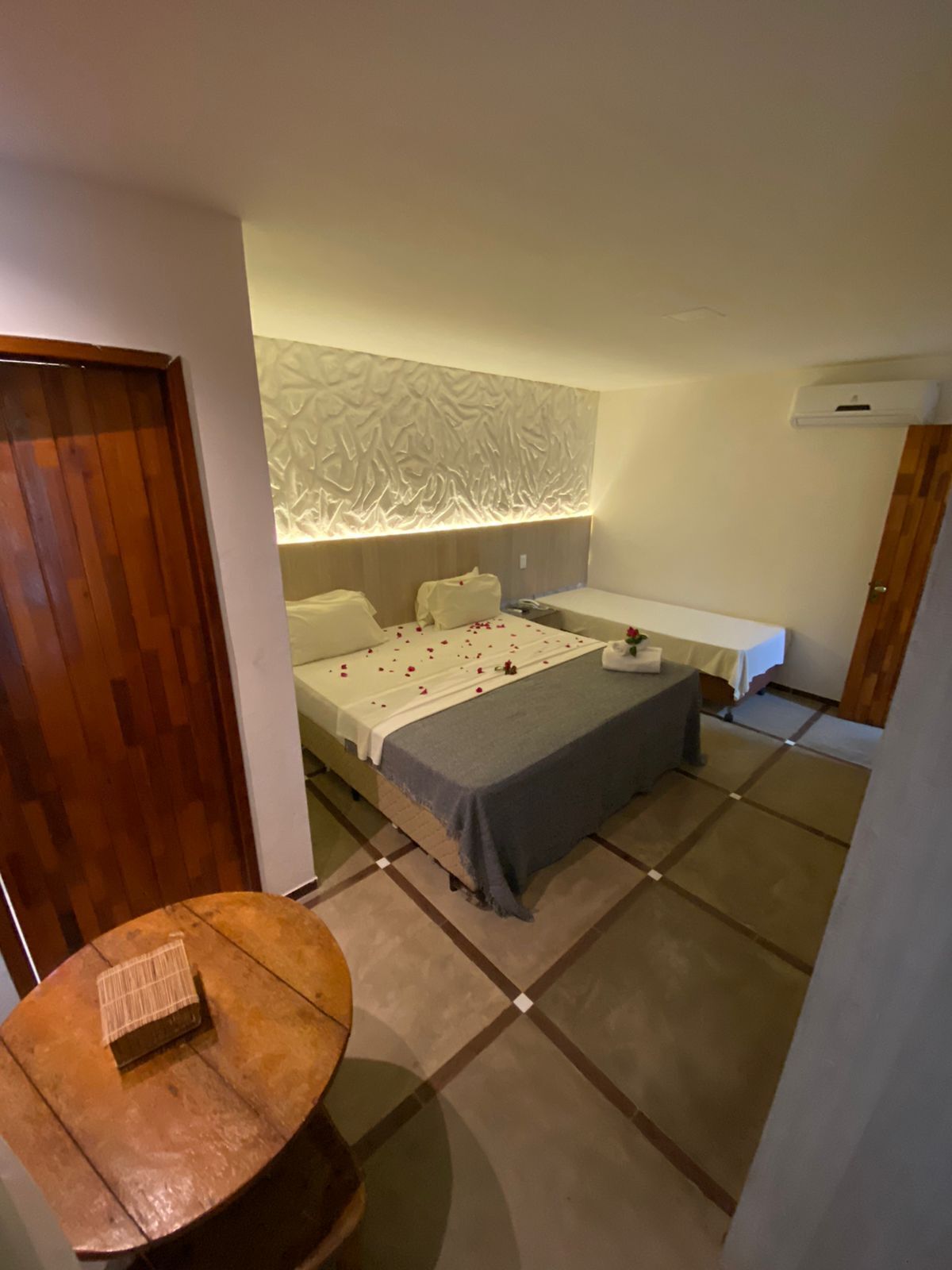 A small, modern bedroom with a bed, bedside tables, and a decorative wall panel.