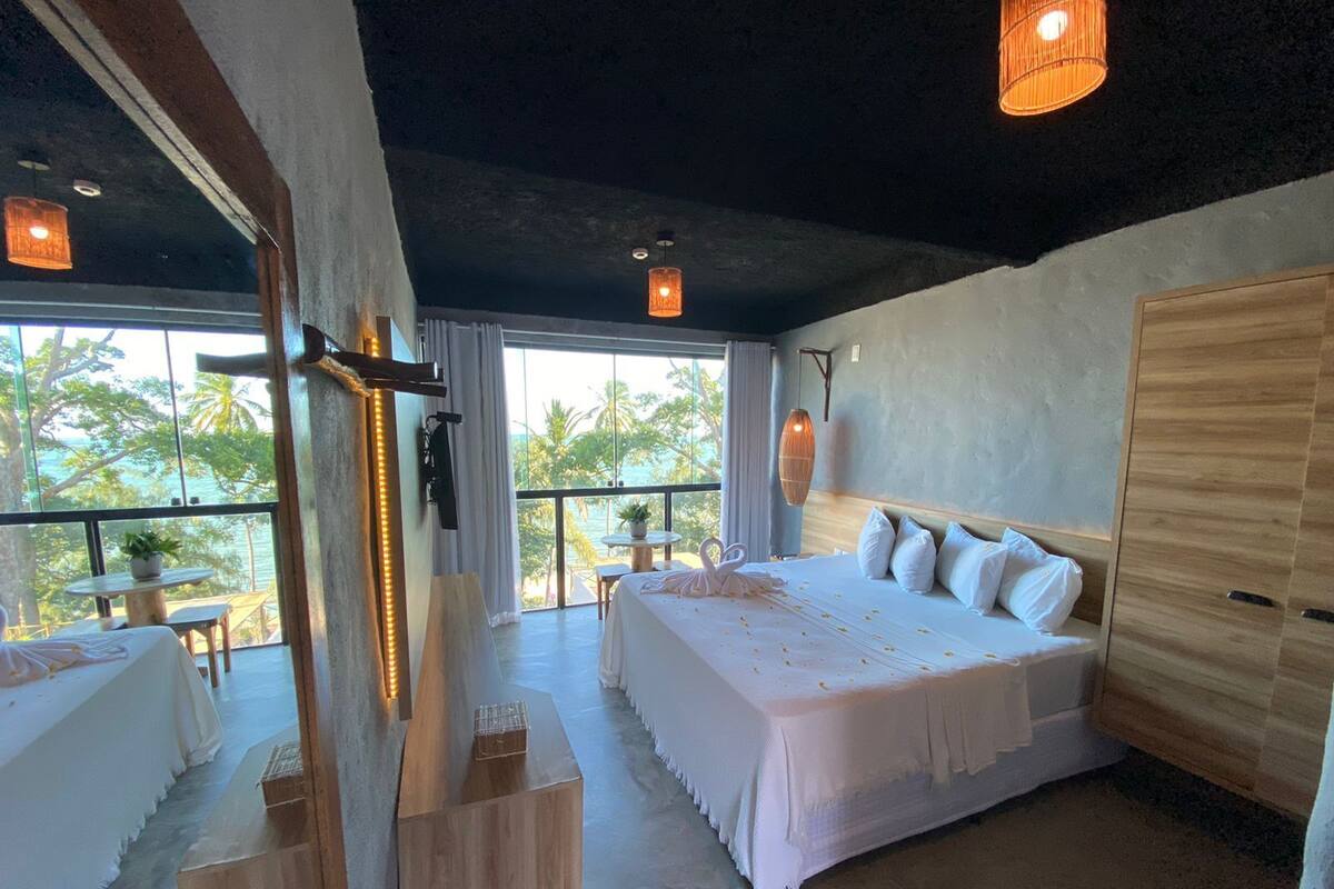 Un dormitorio amplio con una cama grande, un armario de madera y un balcón con vista al océano.