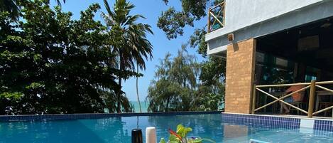 A poolside dining area with a table set for two, surrounded by a pool and palm trees.