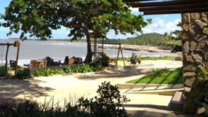 Une terrasse au bord de la plage, agrémentée d’un pilier en pierre, d’une balançoire et offrant une vue sur l’océan.