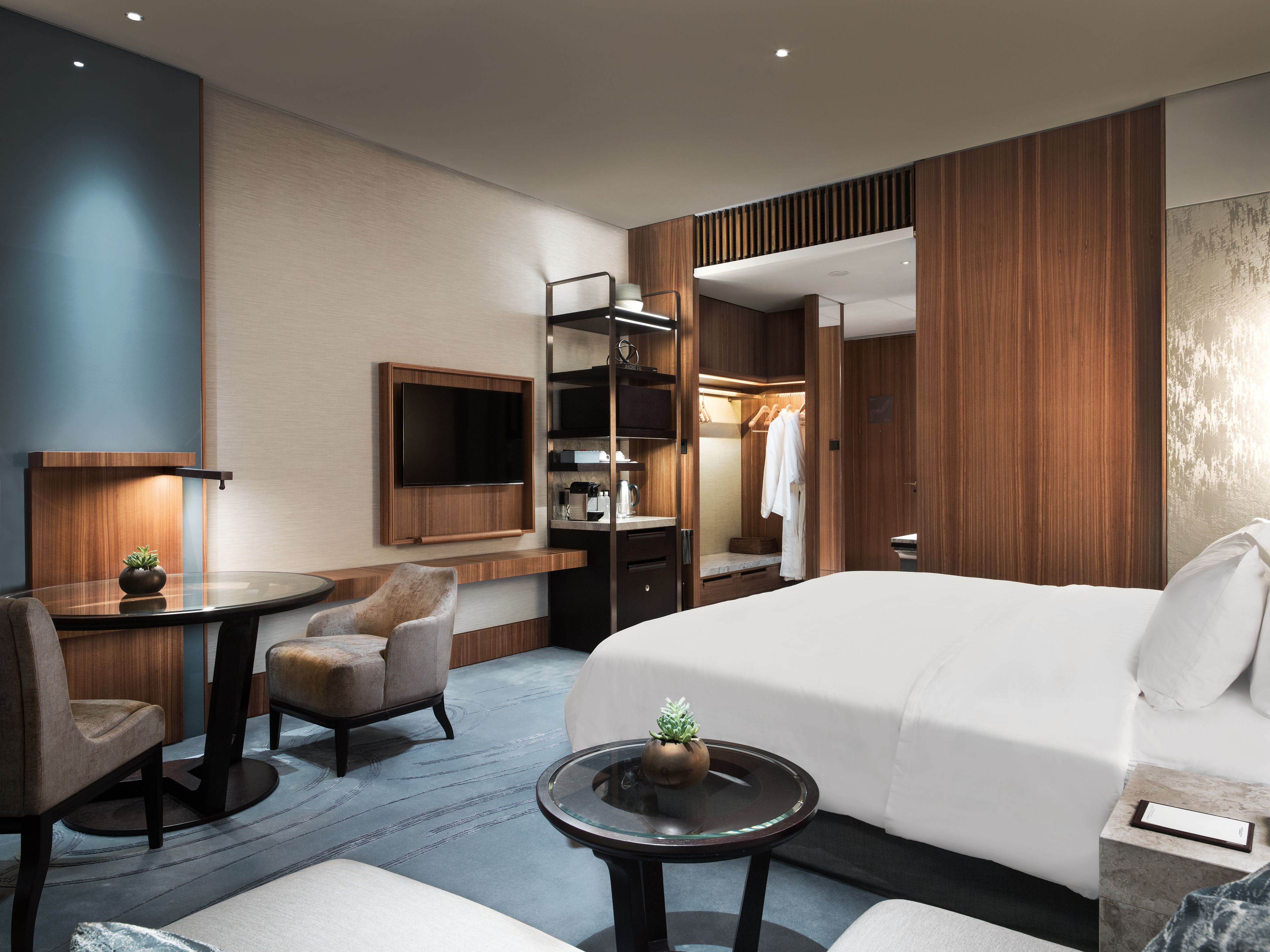 Une chambre d’hôtel moderne équipée d’un lit, d’un bureau, d’une chaise, d’une télévision et d’une armoire.