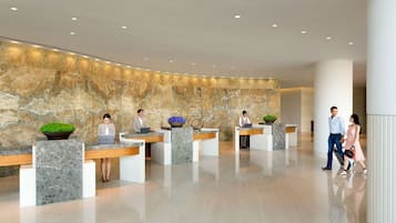A modern reception area with marble walls and multiple reception desks.