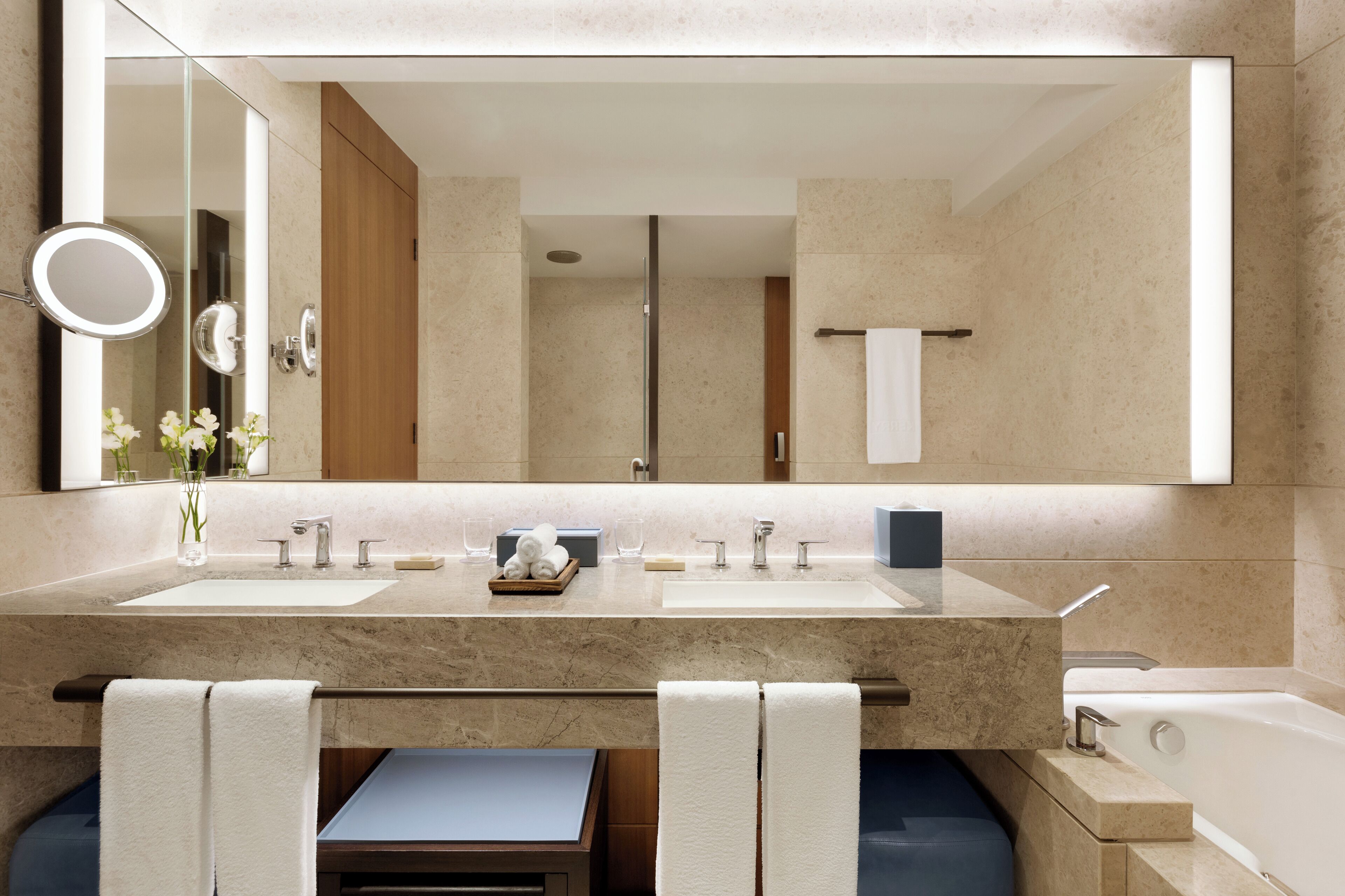 Un baño moderno con dos lavamanos, un espejo grande y una bañera.
