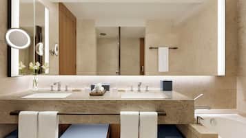 Un baño moderno con dos lavamanos, un espejo grande y una bañera.