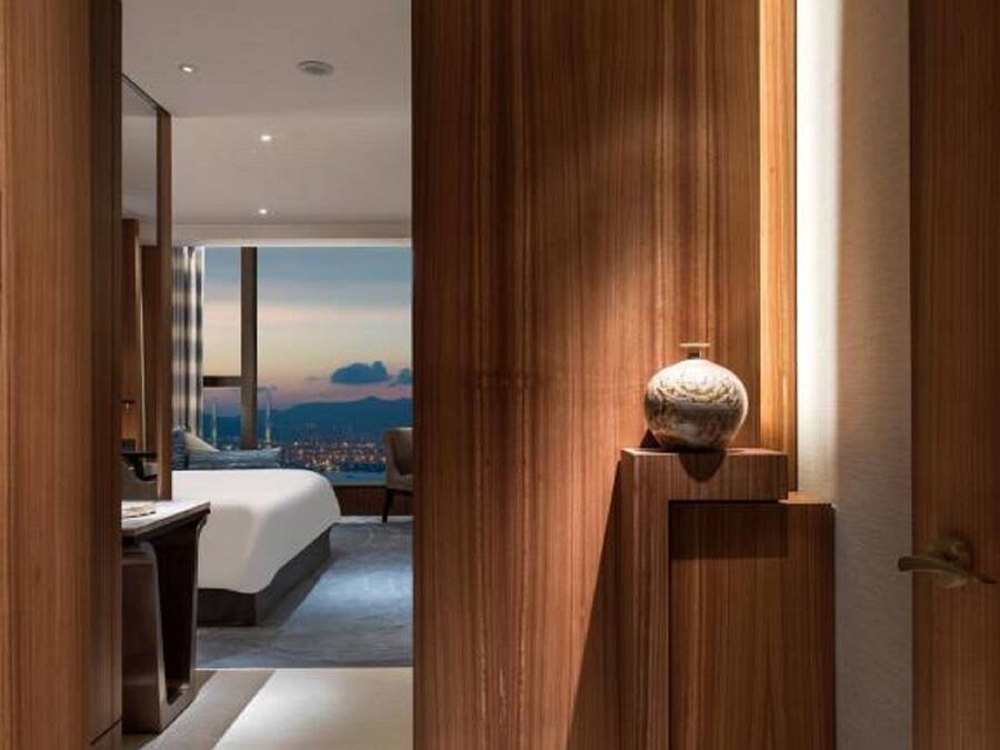 Een moderne hotelkamer met een groot bed, een bureau en uitzicht op een stadslandschap.